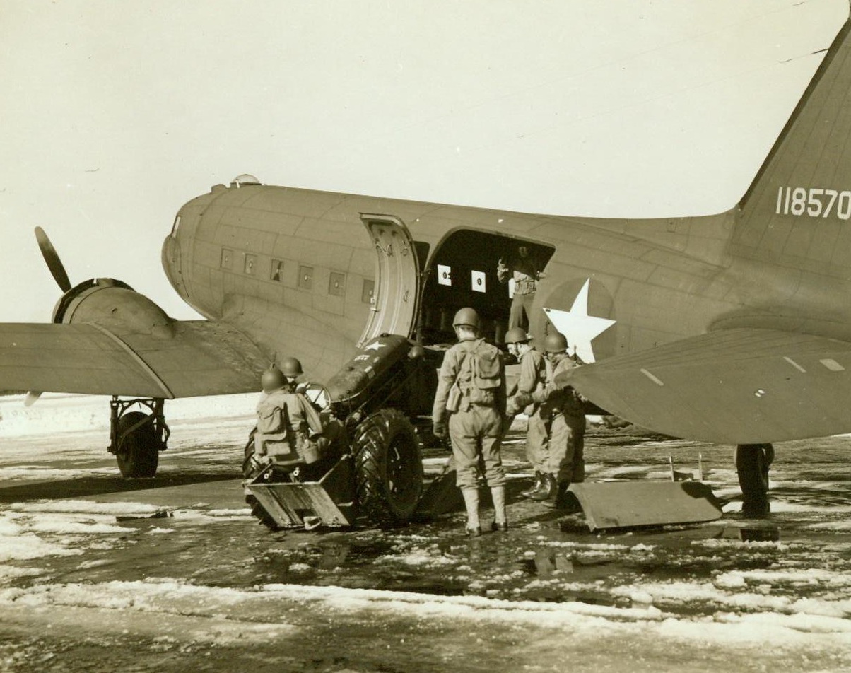 Spring Into Action, 3/3/1943. Westover Field, Mass. – Airborne engineers, training at Westover Field, spring into action as a bomb explosion is reported. Personnel and a tractor are loaded on a C-47 transport plane as the engineers set out to repair the “bombed” airfield. 3/3/43 (ACME);
