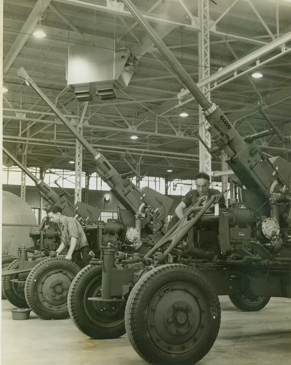 BOFORS ANTI-AIRCRAFT GUNS ROLL OFF PRODUCTION LINES, 8/28/1942. AKRON, OHIO—Skilled workmen turn out more than 30 huge Bofors Anti-aircraft guns at Firestone Tire and Rubber Co. plant here. Above photo shows part of the assembly line of these guns which were originally of Swedish design. They have an effective range of 6000 feet. Credit: OWI Radiophoto from ACME;
