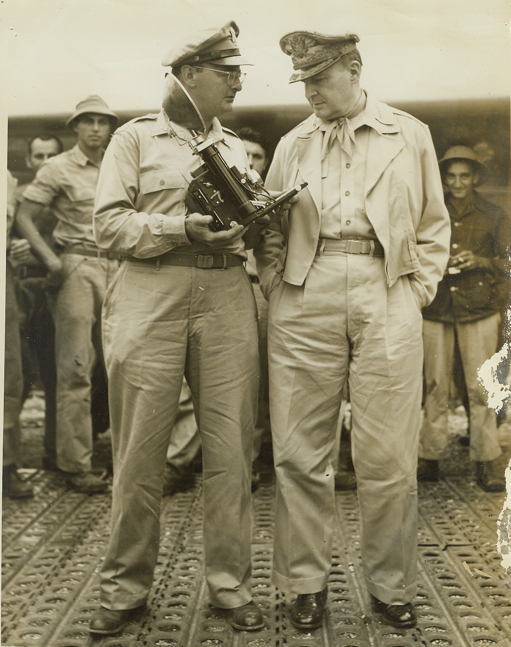 ACME Correspondent With MacArthur, 1/11/1944. NEW GUINEA -- Ware Correspondent Thomas L. Shafer, (left), Photographer for ACME Newspictures, Inc. is shown with Gen. Douglas MacArthur, Supreme Allied Commander in the Southwest Pacific, as Shafer explains the workings of a Speed Graphic Camera.  Credit: ( ACME Photo by Thomas L. Shafer for the War Picture Pool);
