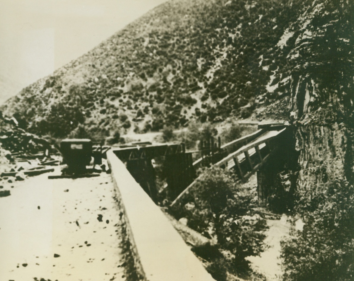 FREEDOM, OR DEATH!”—THE ANDARTES’ CREDO, 3/29/1944. GREECE—High in the mountains of Greece a storm of vengeance is gathering over the heads of Nazi occupation troops that are despoiling this once happy land, and staving, terrorizing and murdering its people. This “storm” is the growing band of Greek patriots, the Andartes, who are training and plotting for the day of Liberation. Even now, “lightning” strikes at German outposts in the form of sharp, deadly Andarte raids, and railway trains and bridges have been blown to bits by these grim, hardy guerillas. Every day, harassed Greek civilians find escape from the “New Order” in the mountain retreats of the Andartes, bringing with them their meager belongings and new tales of Nazi terrorism. The Andartes have sworn that someday, soon, Greece will be free again. The only alternative to their vow, is death. In this series of photos, just released in New York by the Greek Office of Information, activities of the Andartes are shown.  NEW YORK BUREAU EVIDENCE OF ANDARTE ACTIVITY—Here a bridge along a mountain raod in Thessaly has been blown up, blocking the movement of supplies and reinforcements to Nazi mountain outposts. Credit: Acm;