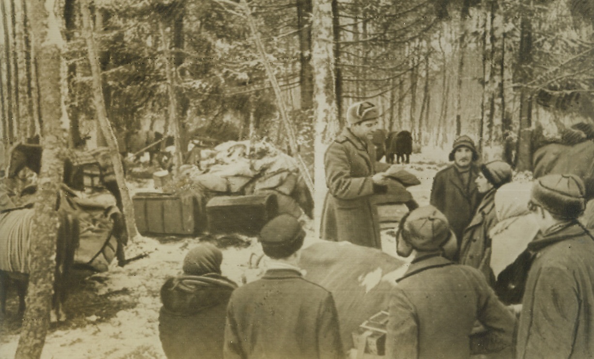 Advancing Reds Meet Forest Dwellers, 3/5/1944. Estonia—Estonians, who took to the wild forests of their country to hide from the Germans, gather around an officer of the Soviet forces now attacking southeast of Vitebsk, near Pskov and Narva. Fighting is fierce for Pskov, the Baltic gateway city almost on the borderline of Russia and Estonia, with the Germans trying to stem the Red Tide along an intricate network of “hedgehog” defenses. Credit: ACME radiophoto;