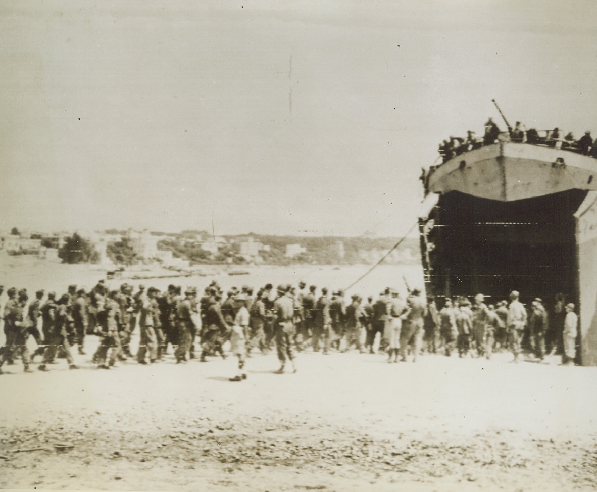 All Aboard for a POW Camp, 5/29/1944. ANZIO, ITALY—A long line of German prisoners from the Anzio beachhead tramp into the yawning mouth of an LST that will take them to another prisoner of war encampment. The luckless enemy soldiers were among the first caught in the swift tide of advancing Allied troops in Italy. Credit: U.S. ARMY RADIOTELEPHOTO FROM ACME.;