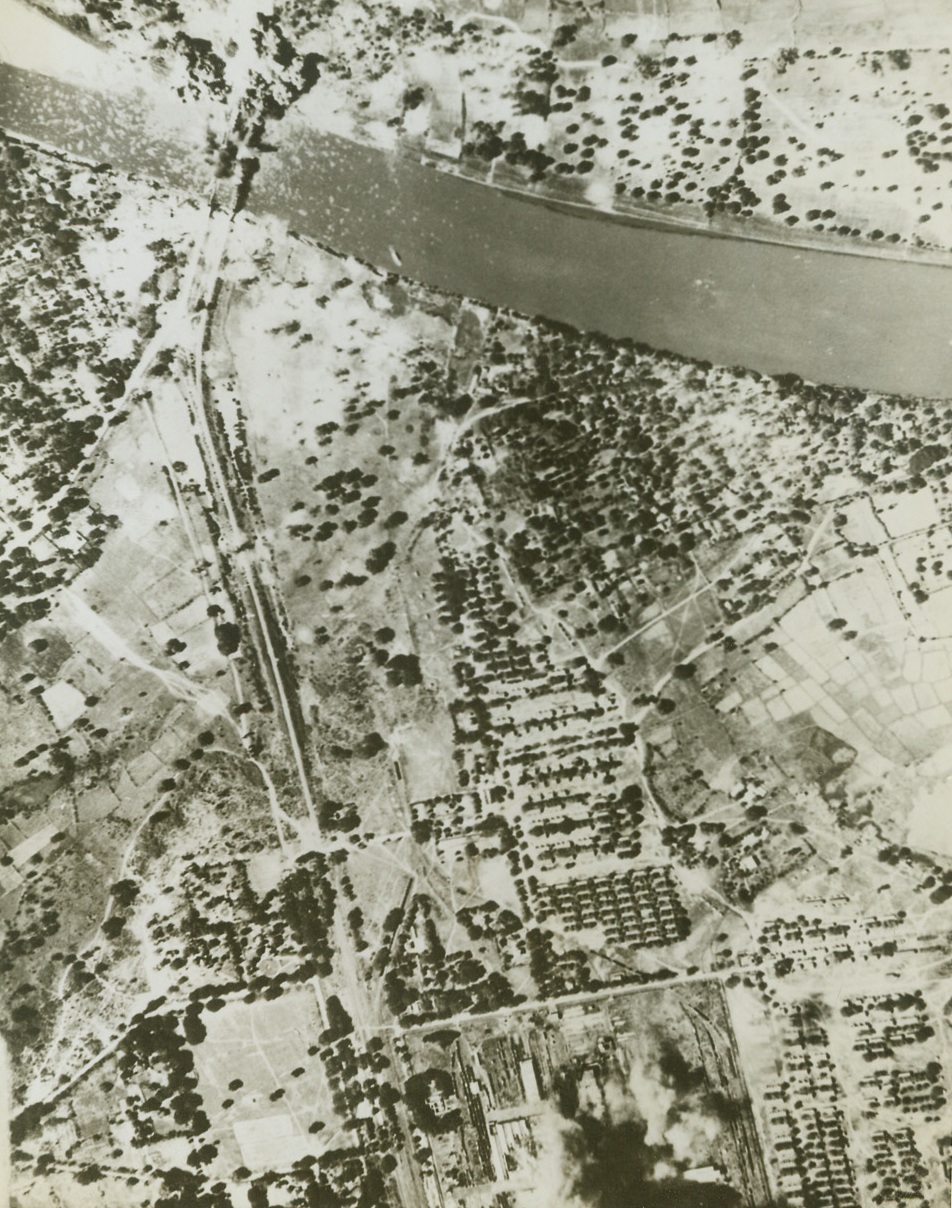 Bombing Jap-Occupied Burma. An aerial view of two simultaneous raids on important objectives in Jap-occupied Burma. The picture shows bombs from American aircraft bursting in a Jap railroad yard (at left) and blowing up twin bridges near the town of Myitnge (top right). The bomb bursts are about a mile apart. The bridges carry main north-south communications in Burma. Credit: ACME;